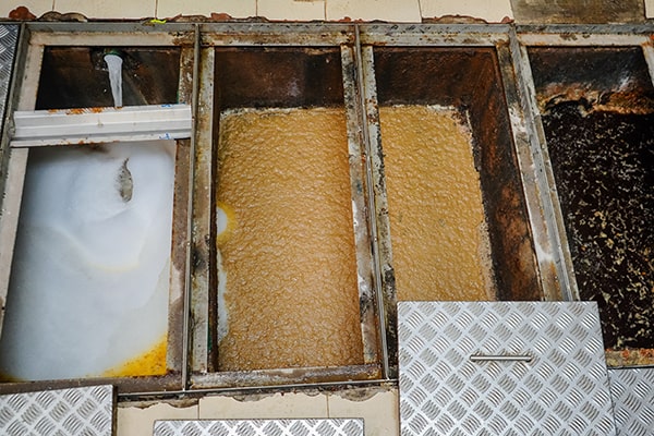 grease trap maintenance involves removing and disposing of grease and solid waste buildup from the trap